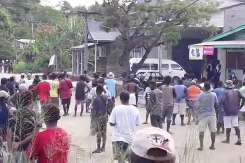 Crowds of people mass near a police station in Honiara