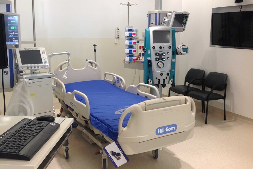 A bed and medical equipment in a hospital intensive care unit room.
