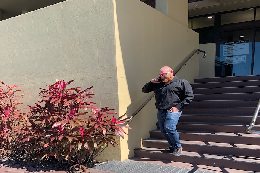 Man walking down courthouse steps while talking on phone. 