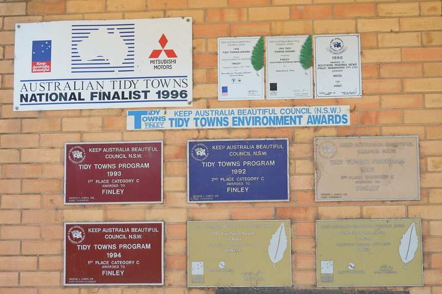 A wall with 'Tidy Town' award plaques for the town of Finley in Australia.