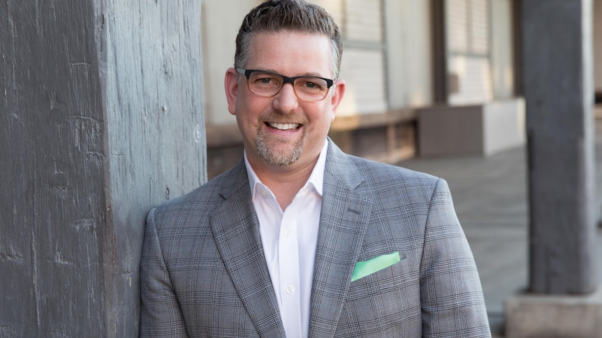 a man in a suit and glasses smiles