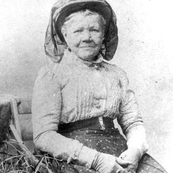 old black and white image of old lady seated with large hat