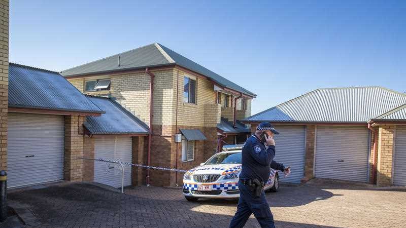 Policeman speaks on the phone outside a brick townhouse in Northgate where a toddler was injured and later died.