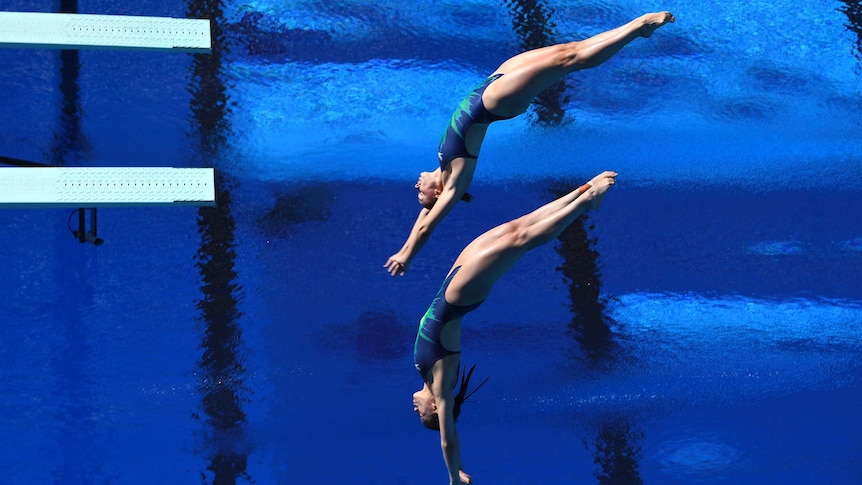 Georgia Sheehan and Esther Qin diving into the water at the Gold Coast Aquatic Centre.