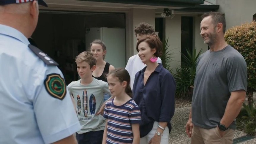 Group of people stand outside house