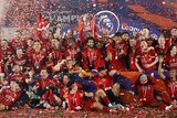 Confetti flies through the air as a jubilant Premier League champion team celebrates with trophy.