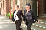 Vanessa Amorosi wearing a black pant suit with her hair tied back and glasses walking out of court