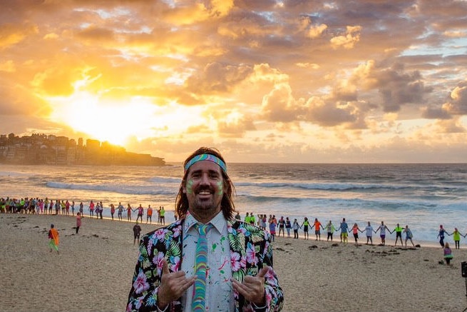 Grant Trebilco and people wearing fluoro gathered at Bondi Beach at dawn for OneWave's fourth anniversary.