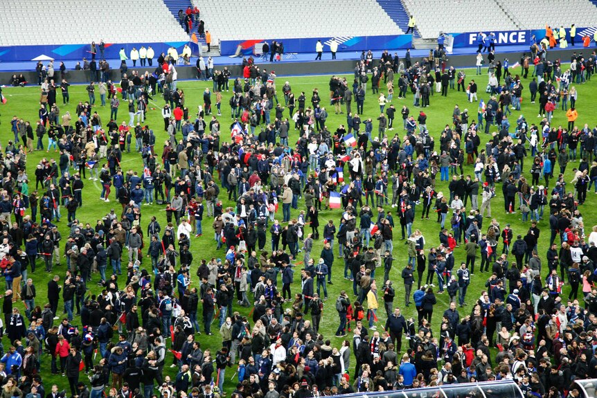Spectators wait on the pitch of the Stade de France stadium