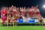 an australian rules football team stand on a podium holding a premiership flag