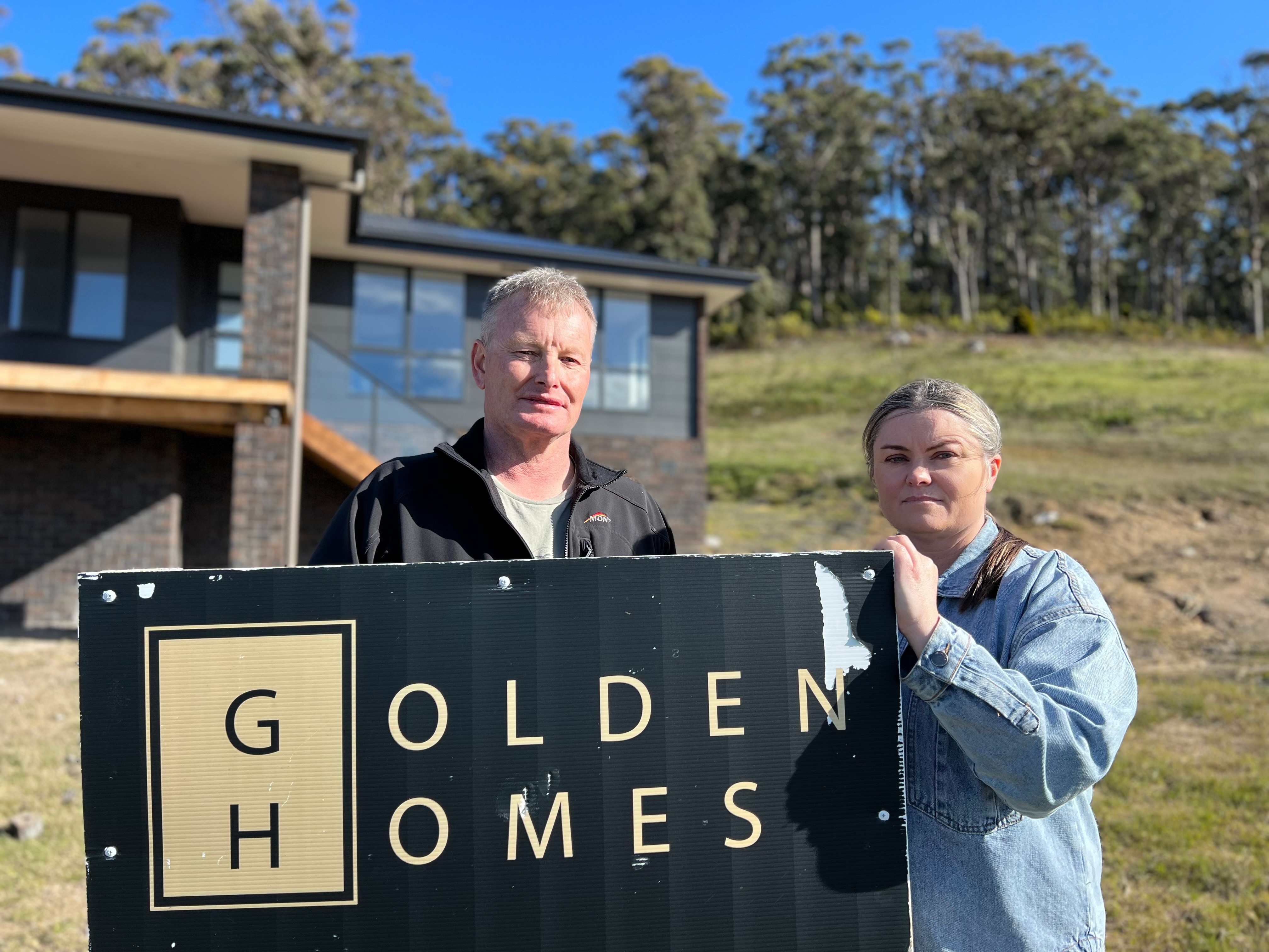 Tasha Jordan and Ken Belbin standing next to the Golden Homes sign.