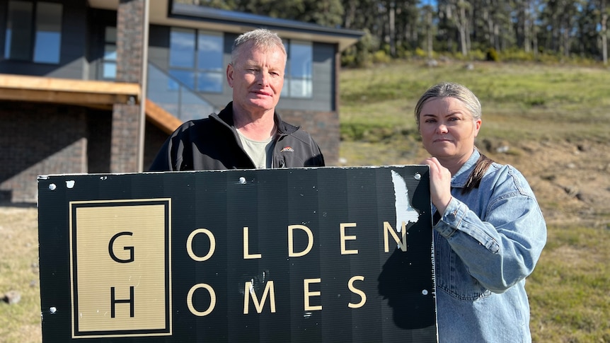 Tasha Jordan and Ken Belbin standing next to the Golden Homes sign.