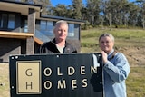 Tasha Jordan and Ken Belbin standing next to the Golden Homes sign.