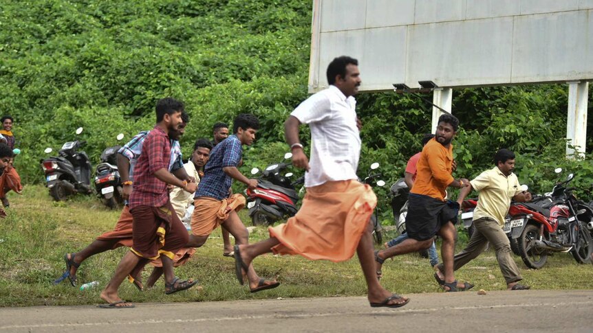 Male protesters running away from police outside the temple after they stopped women from entering the building