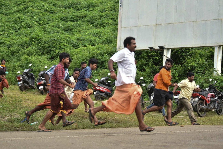 Male protesters running away from police outside the temple after they stopped women from entering the building