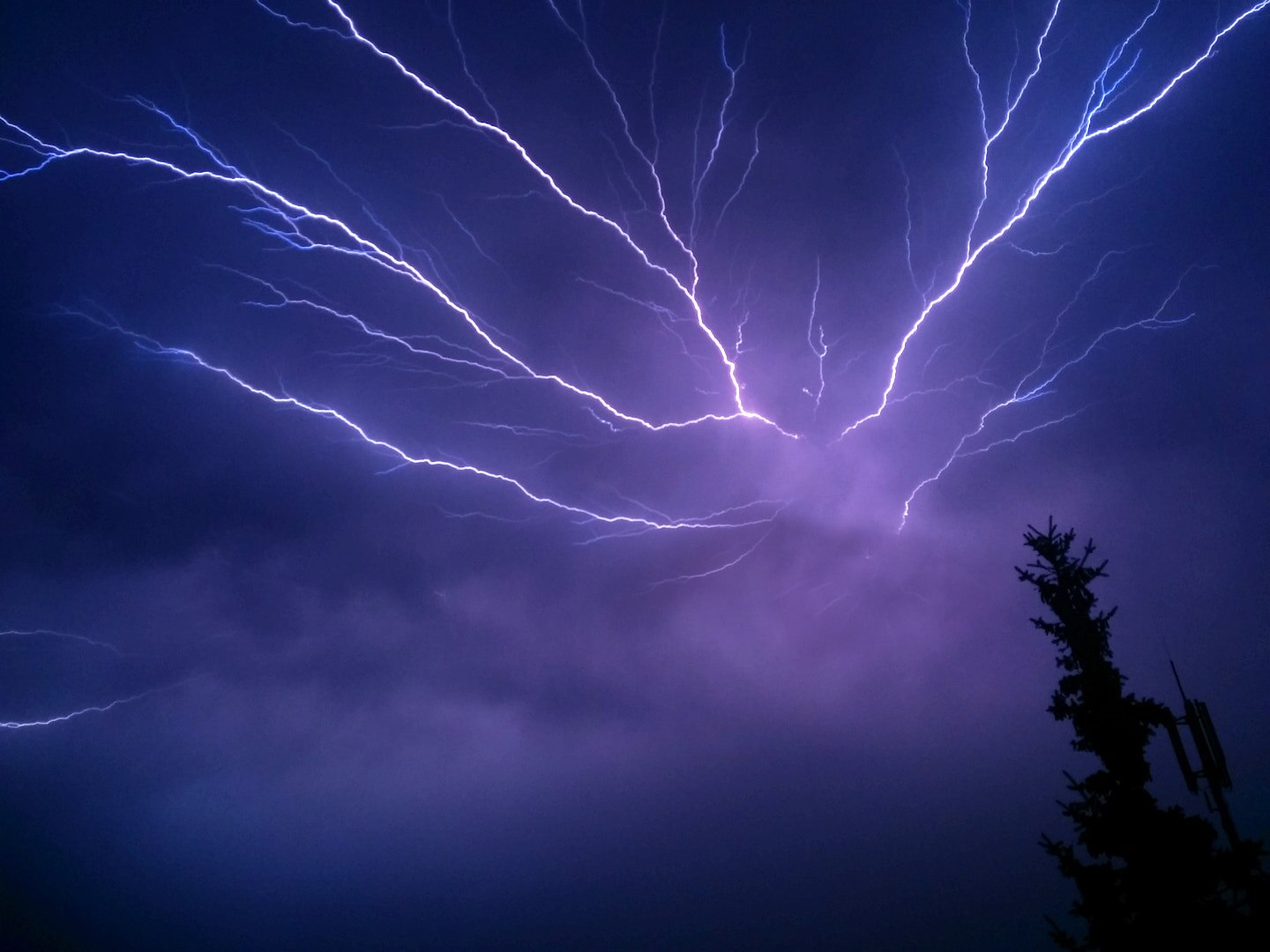 A white bolt of lightning extends over a dark cloudy sky.