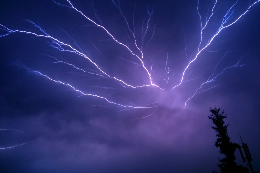 A white bolt of lightning extends over a dark cloudy sky.