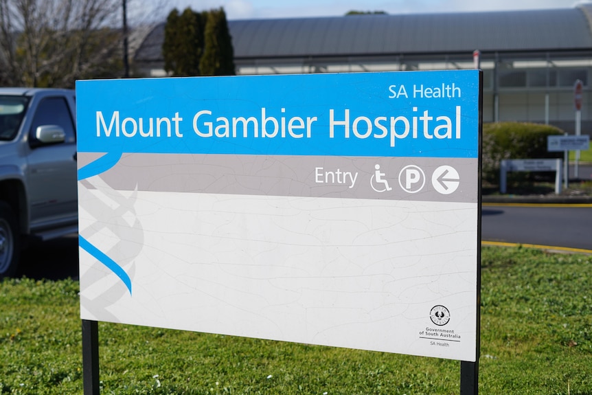 A blue and white sign reading 'Mount Gambier Hospital' with a car park in the background