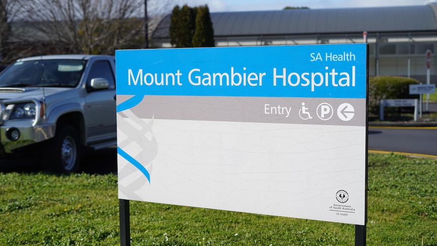 A blue and white sign reading 'Mount Gambier Hospital' with a car park in the background
