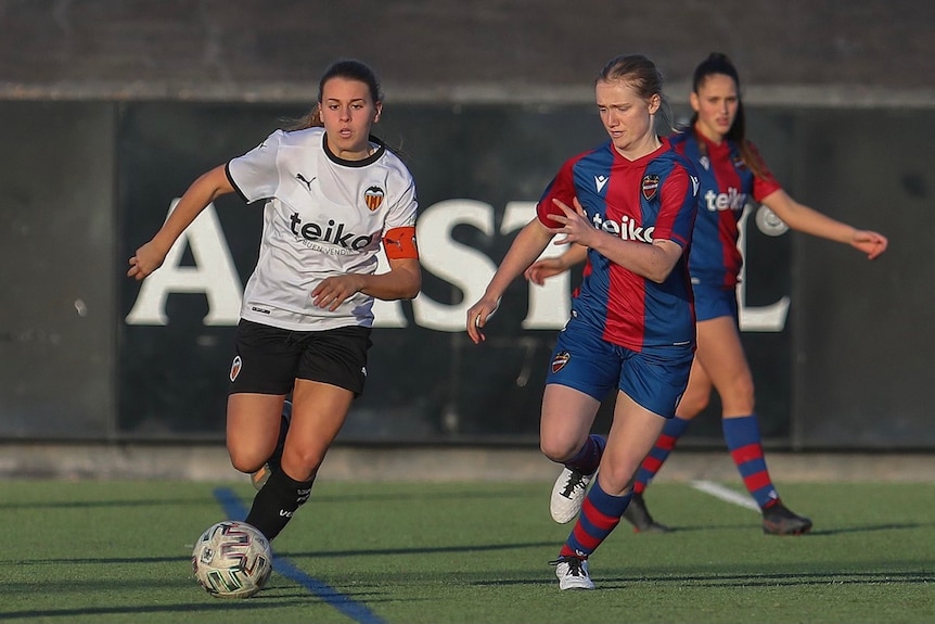 Two female soccer players run for the ball