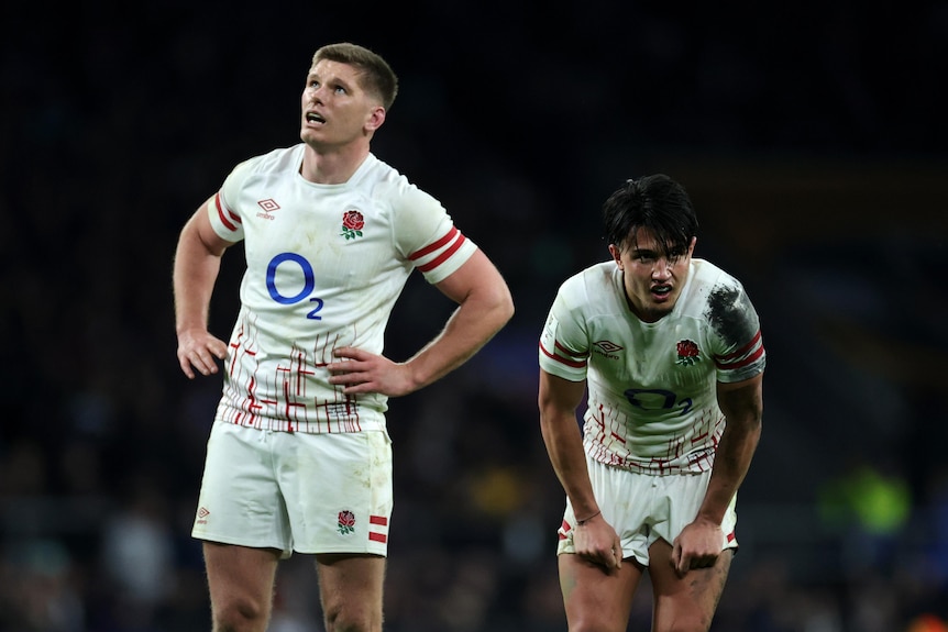 Owen Farrell looks up and Marcus Smith bends down next to him