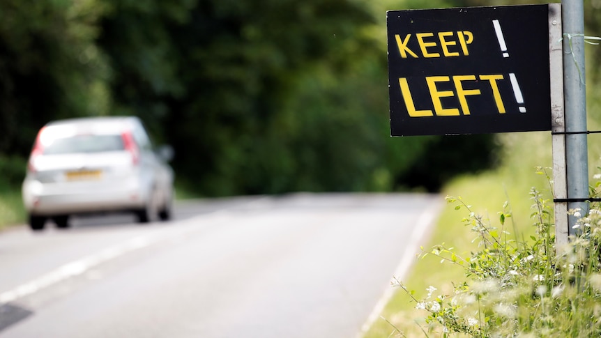 A sign by the road side reads KEEP! LEFT!