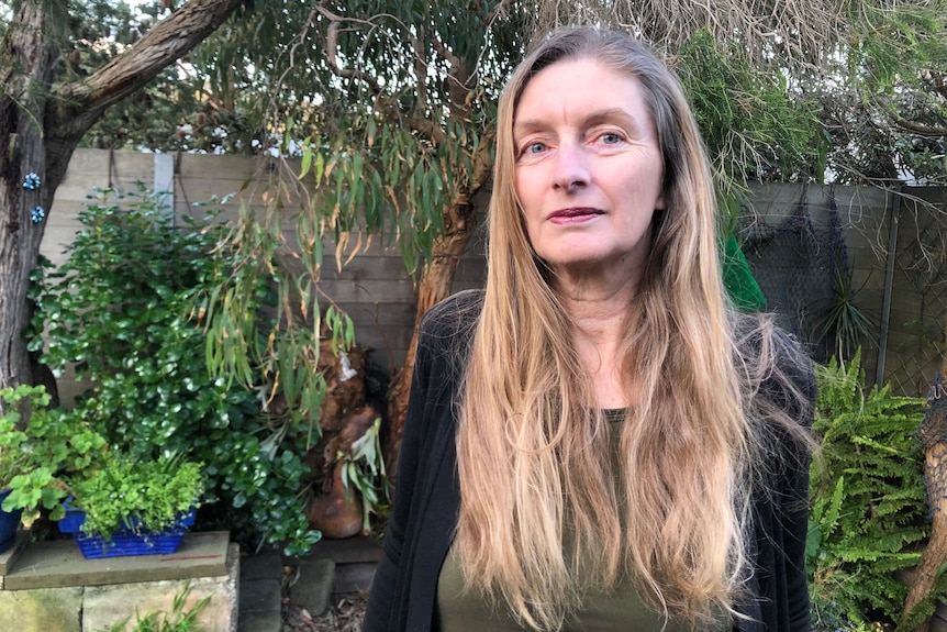 A woman with long hair standing in a garden.