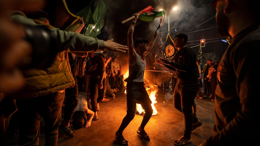 Palestinians dance in the street with Palestinian flags to celebrate the announcement of a cease-fire.