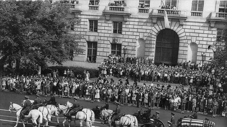 Black and white photo of Franklin Roosevelt casket carried by horse-drawn carriage passes by people on the street