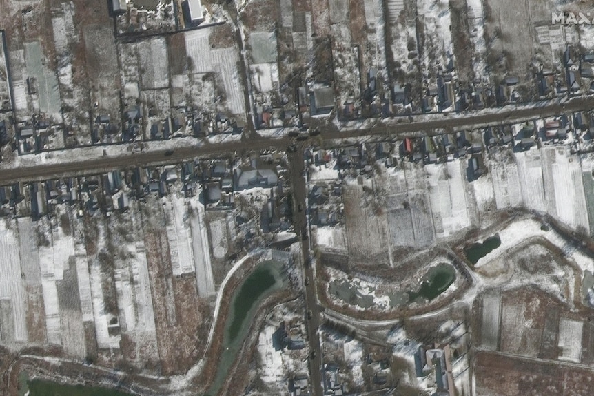 A satellite image shows a number of military tricks arranged along a road in a snowy village