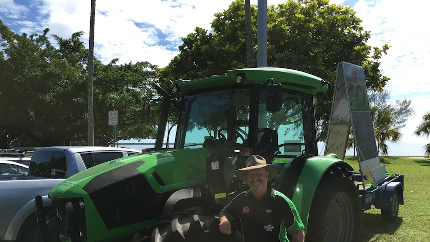 Farmer Greg Dennis standing beside a bright green tractor on Cairns esplanade