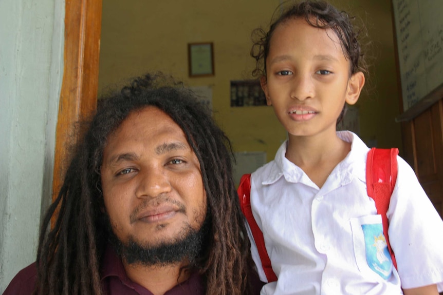 Juvinal Dias from the Timor-Leste organisation La’o Hamutuk, sitting beside his young daughter Paya.