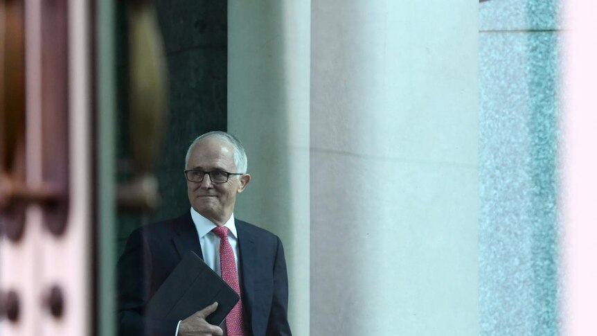 Prime Minister Malcolm Turnbull smiles while holding a folder under his arm