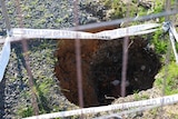 a large hole behind a fence.
