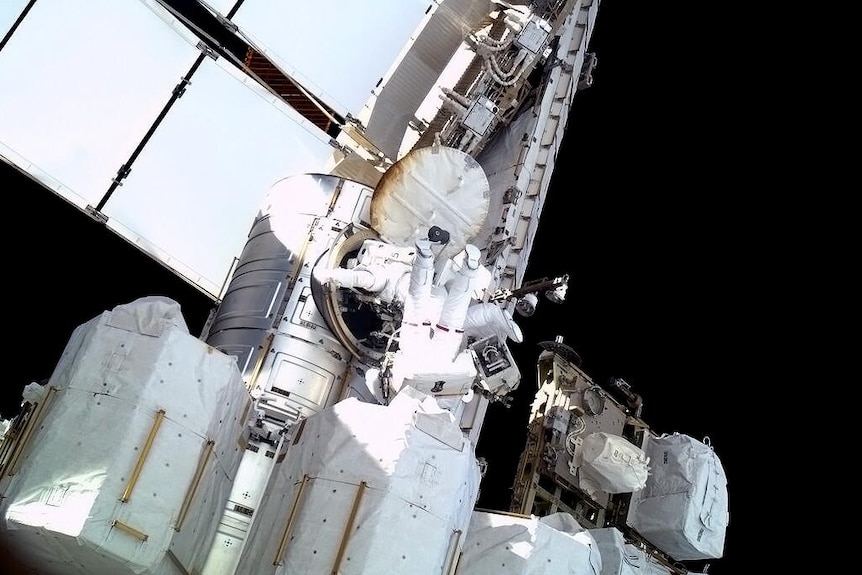 Astronauts climb out of ISS airlock
