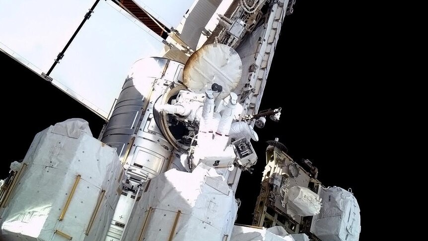 Astronauts climb from airlock.