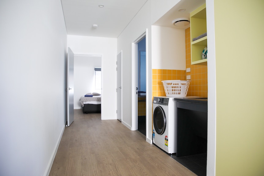 A laundry sitting off a corridor which leads to a bedroom. 