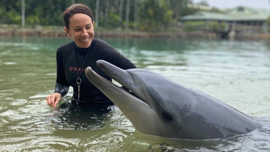 A dolphin 'smiling' with its trainer also smiling in the water at SeaWorld on the Gold Coast.