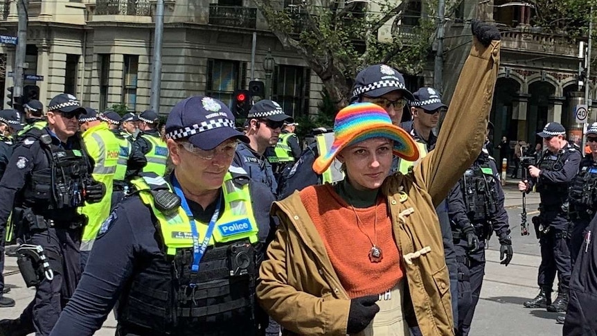 A police officer leads a climate change protester away after being arrested in Melbourne.