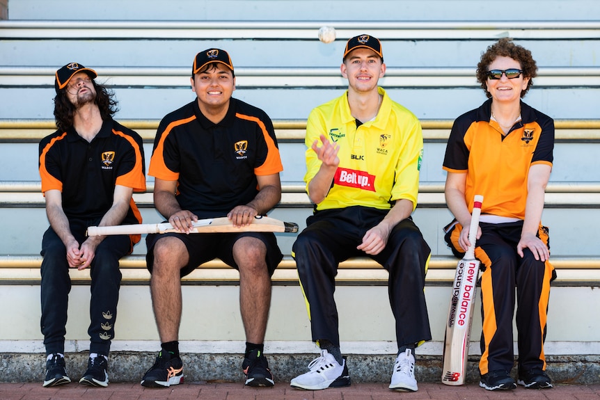 Four cricketers sitting on a bench.