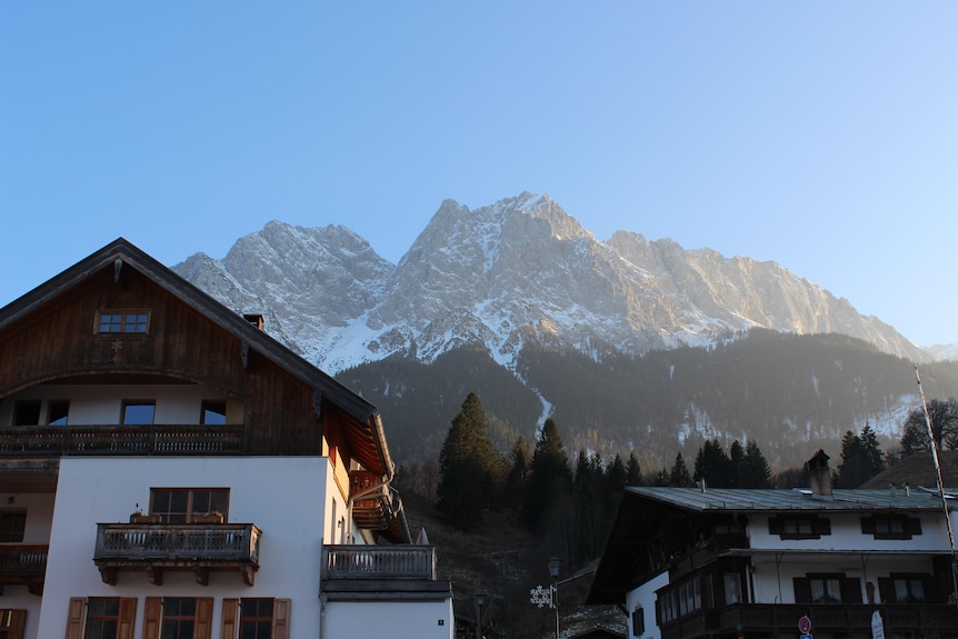Rustic German homes in the foreground with snow-capped peaks behind