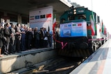 Iranian officials applaud on the platform as the train arrives.