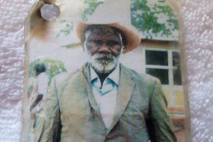 A printed out photo of an Indigenous man in a suit and cowboy hat.