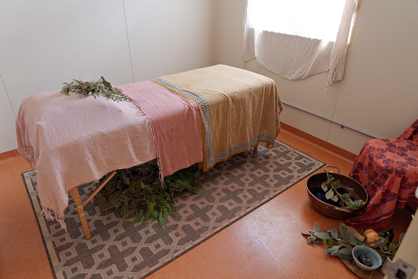 A massage table with leaves and healing products.