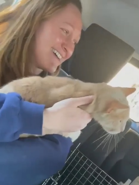 Femme étreignant un chat roux dans une voiture