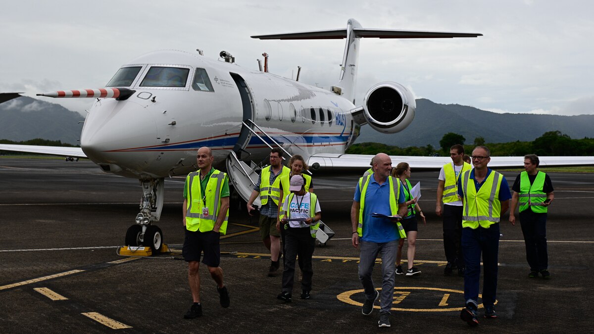 group of people in high-vis vests walk from jet plane on tarmac