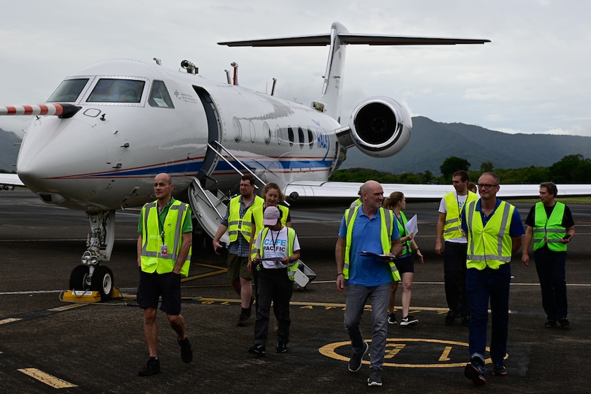 group of people in high-vis vests walk from jet plane on tarmac