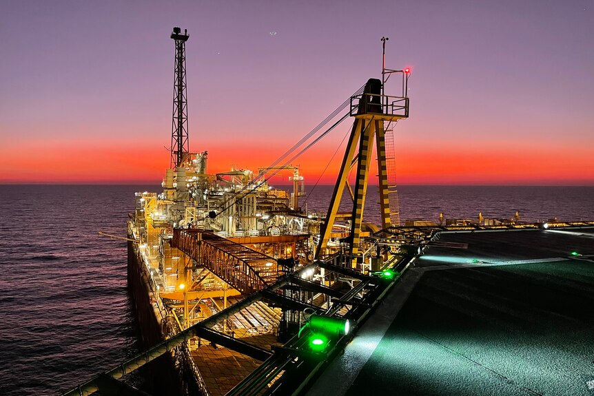 a floating oil production vessel with a sunset in the background