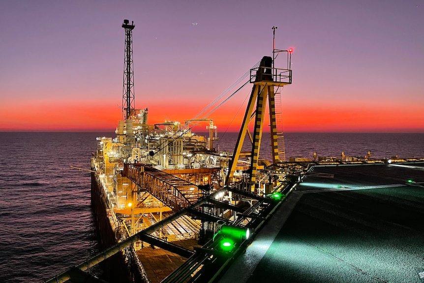 a floating oil production vessel with a sunset in the background