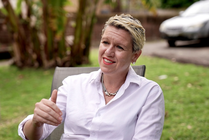 Brynn O'Brien seated in a garden, wearing a white shirt.